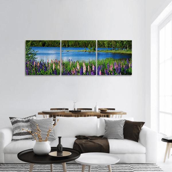 Lupine Field by Calm Lake Panoramic Canvas Wall Art in green, blue and purple, hung on a wall