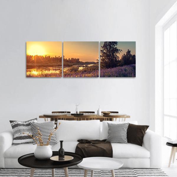 Sunset Lupines by the River Panoramic Canvas Wall Art in orange, yellow and purple, hung on a wall