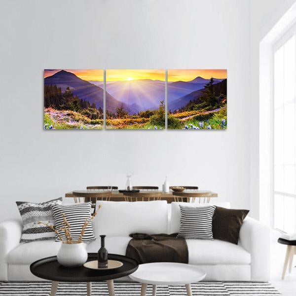 Sunrise Over Wildflower Meadow and Mountains Panoramic Canvas Wall Art in yellow, green and purple, hung on a wall