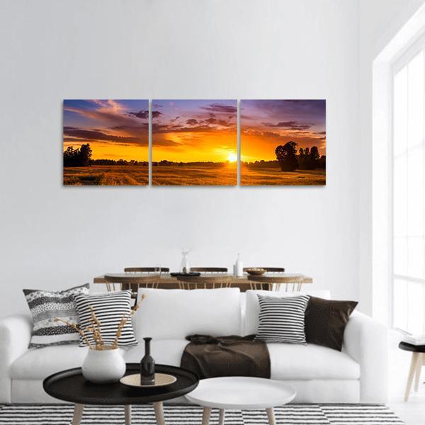 Summer Sunset Over Fields Panoramic Canvas Wall Art in orange, yellow and purple, hung on a wall