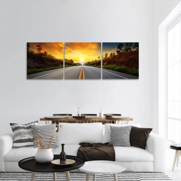 Sunrise Over Asphalt Road with Double Yellow Lines Panoramic Canvas Wall Art in gray, orange and yellow, hung on a wall