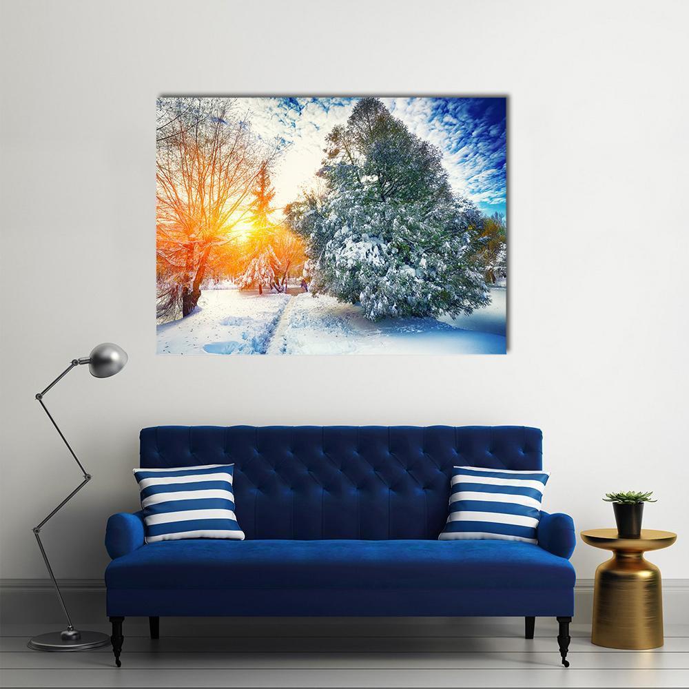 Winter Sunlight Through Snowy Pine Trees Canvas Wall Art in white, orange and blue, single panel hung on a wall