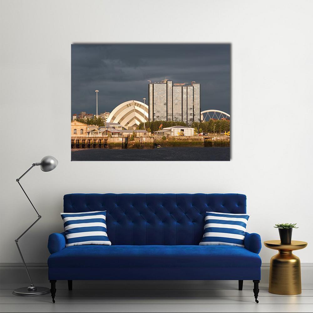 Sunlit Buildings Against Storm Clouds Canvas Wall Art in gray, yellow and blue, single panel hung on a wall