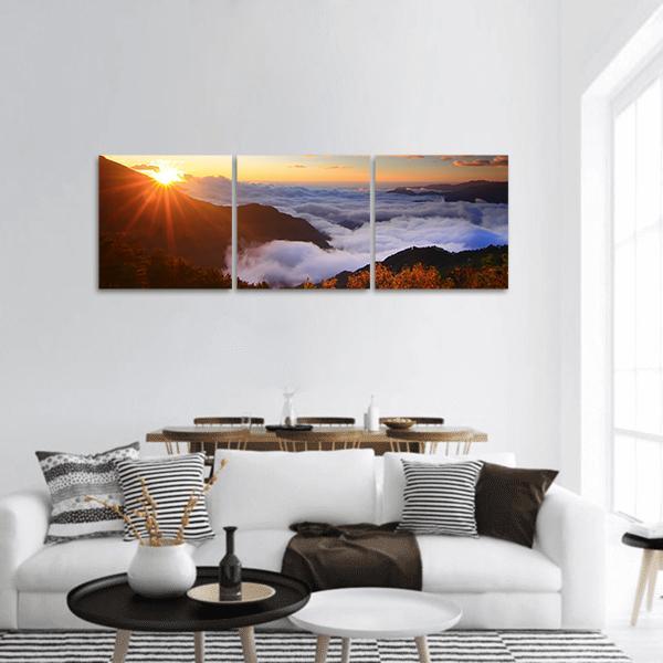 Sunrise Over Mountains and Sea of Clouds Panoramic Canvas Wall Art in white, orange and blue, hung on a wall