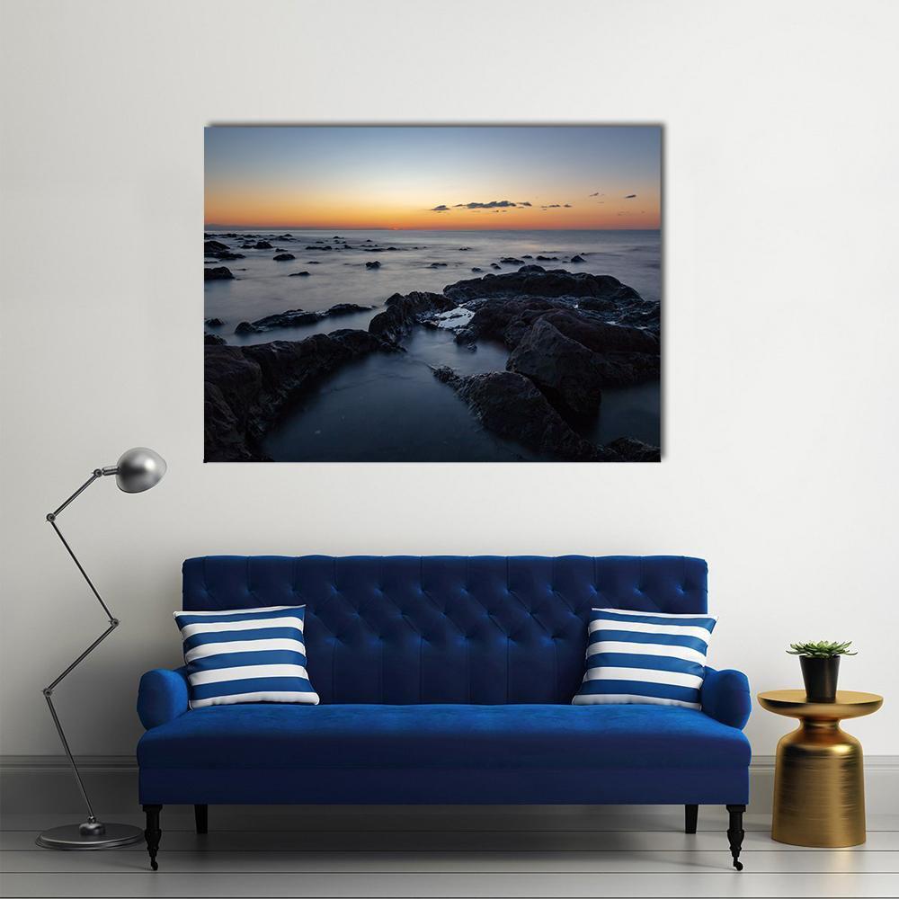 Sunrise Over Palmasera Beach Canvas Wall Art in black, orange and blue, single panel hung on a wall