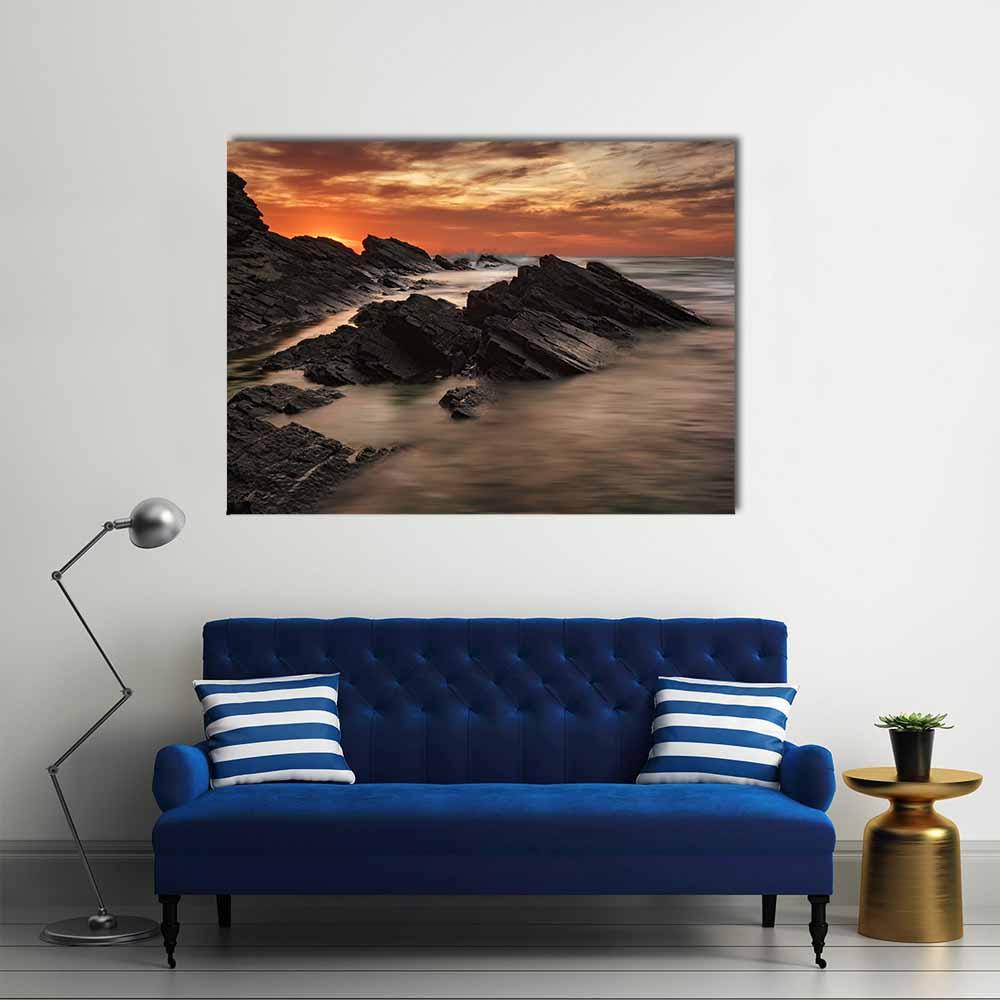 Sunset Over Jagged Coastal Rocks Canvas Wall Art in black, brown and orange, single panel hung on a wall