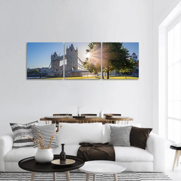Sunrise Over Tower Bridge, London Panoramic Canvas Wall Art in yellow, green and blue, hung on a wall