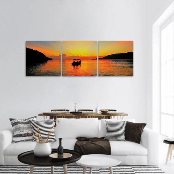 Tropical Sunset with Boat Silhouette Panoramic Canvas Wall Art in black, orange and yellow, hung on a wall