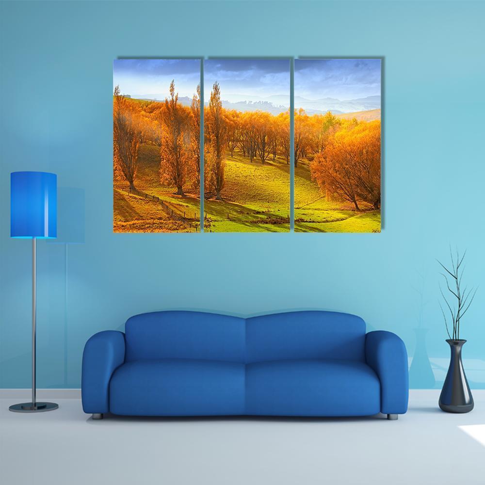 Autumn Sunrise Over Rolling Hills Canvas Wall Art in orange, yellow and blue, 3 panel horizontal set hung on a wall