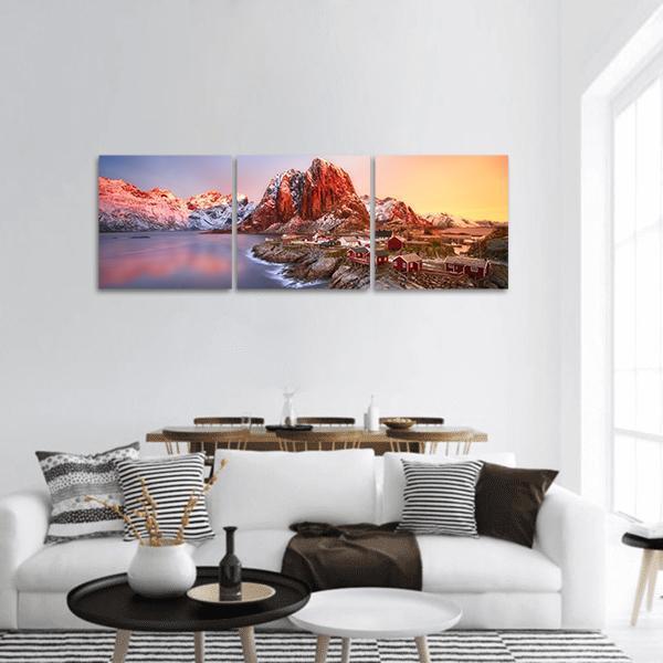 Sunrise Over Hamnoy, Lofoten Islands Panoramic Canvas Wall Art in red, orange and blue, hung on a wall