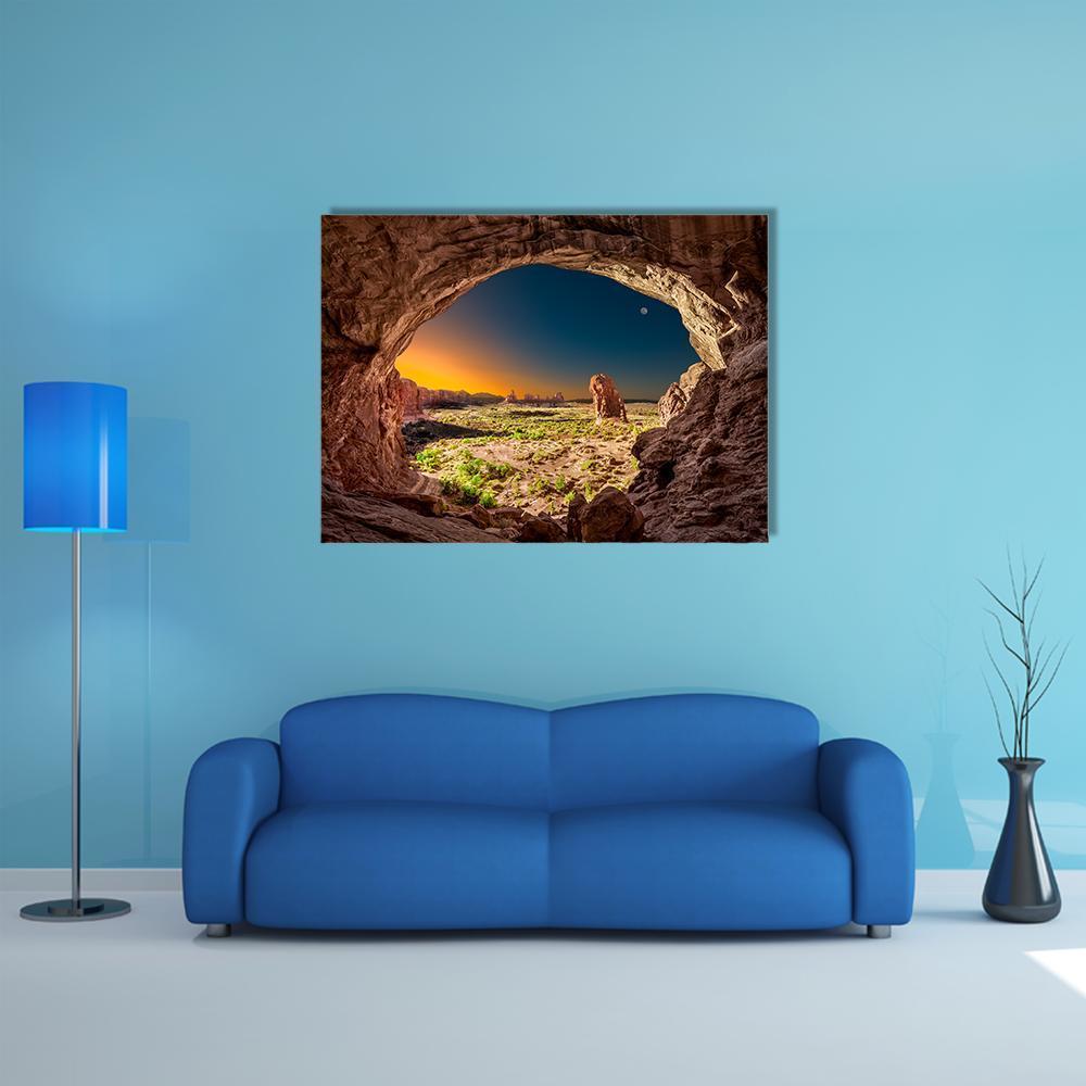 Sunrise Through Double-arched Cave Canvas Wall Art in brown, orange and blue, single panel hung on a wall