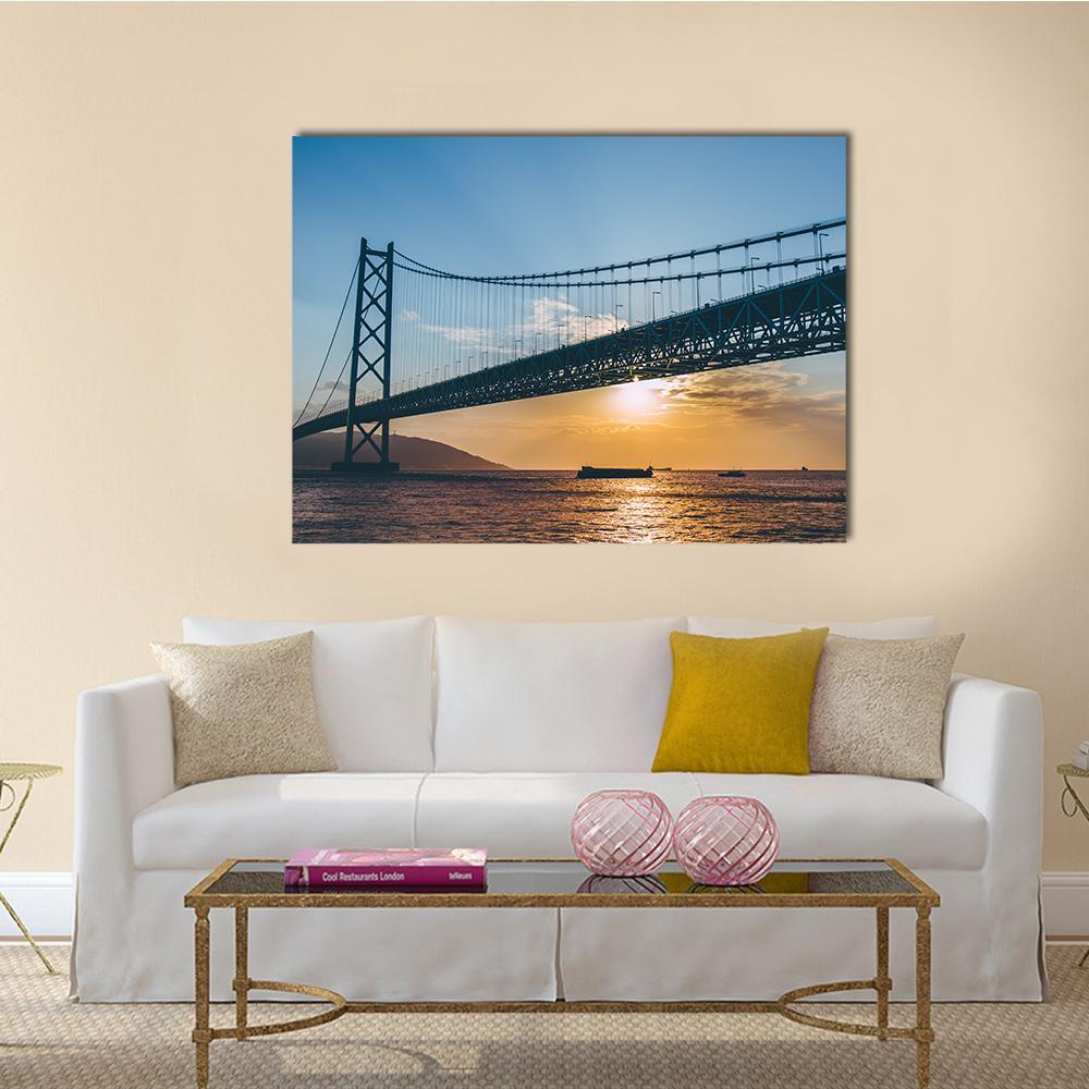 Sunset Over Suspension Bridge and Cargo Ships Canvas Wall Art in orange, yellow and blue, single panel hung on a wall