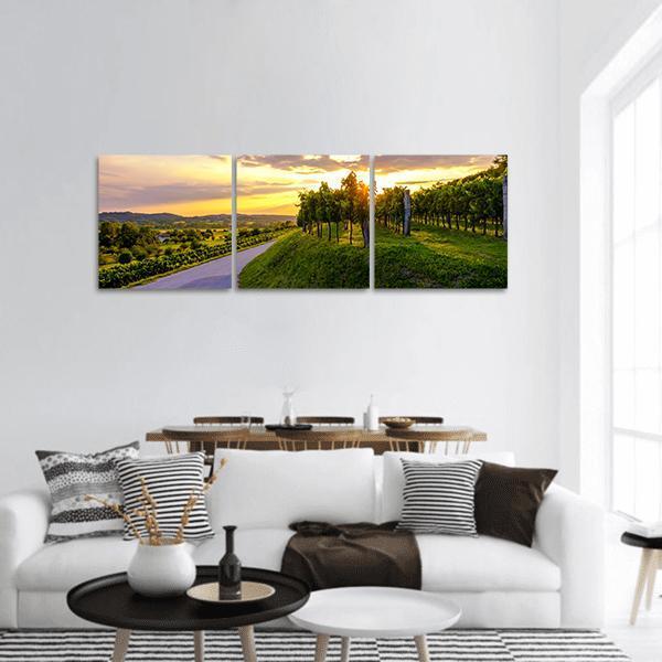 Sunset Over Vipava Vineyards Panoramic Canvas Wall Art in orange, yellow and green, hung on a wall
