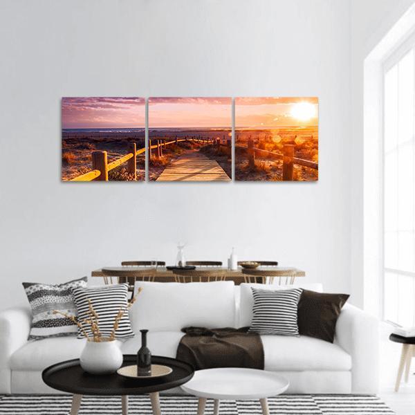 Sunset Beach Boardwalk at Dusk Panoramic Canvas Wall Art in brown, orange and pink, hung on a wall