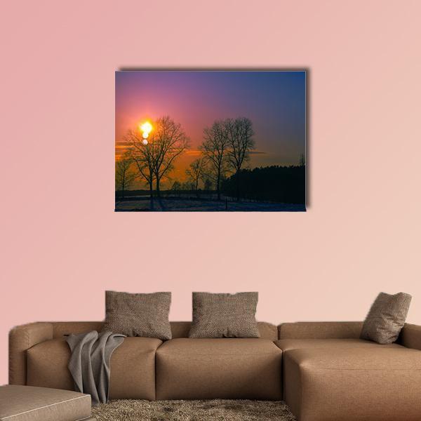 Winter Sunset Over Bare Trees Canvas Wall Art in orange, blue and purple, single panel hung on a wall