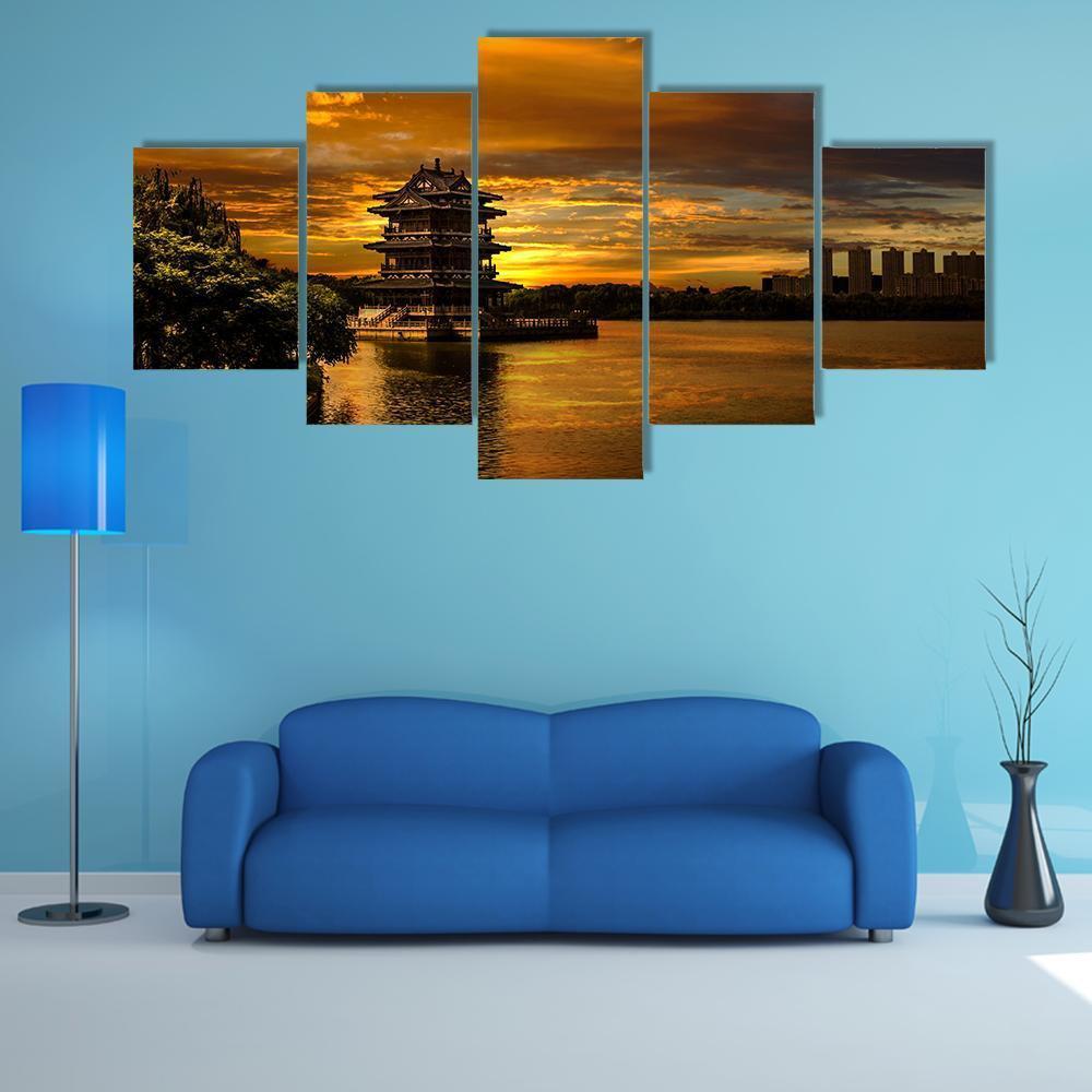 Pagoda at Sunset Over Water Canvas Wall Art in black, orange and yellow, 5 panel Star layout hung on a wall