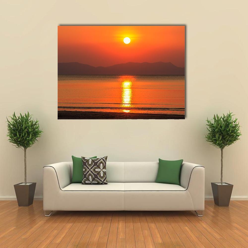 Beach Sunset Over Ocean and Mountains Canvas Wall Art in red, orange and yellow, single panel hung on a wall