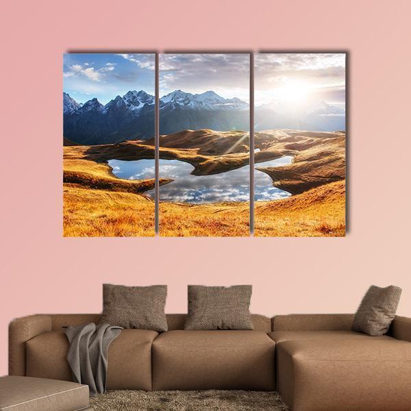 Sunset Over Mountain Lake Canvas Wall Art in orange, yellow and blue, hung on a wall