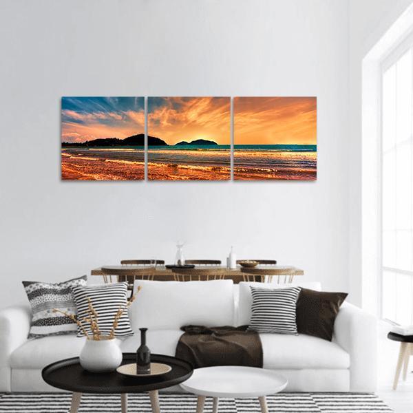 Golden Hour Beach with Distant Mountains Panoramic Canvas Wall Art in gold, orange and blue, hung on a wall