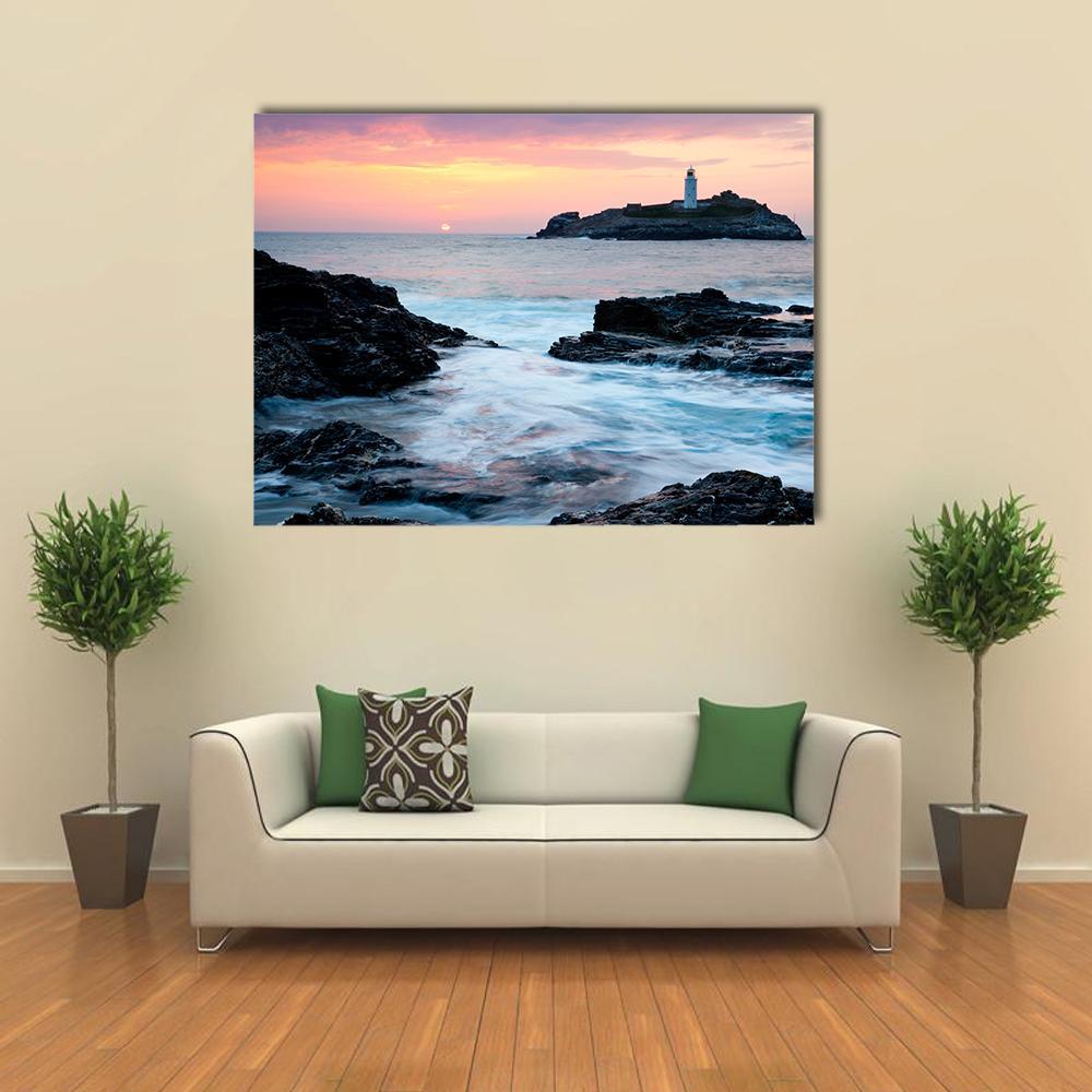 Sunset Over Rocky Cliffs and Lighthouse Canvas Wall Art in orange, blue and pink, single panel hung on a wall