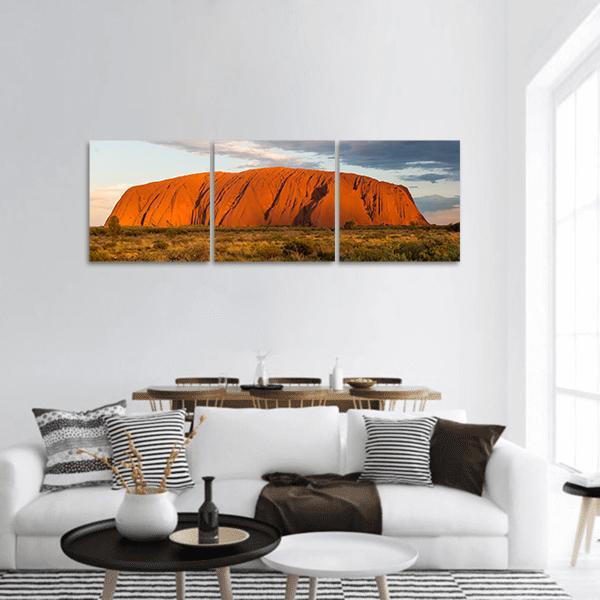 Sunset Over Ayers Rock Panoramic Canvas Wall Art in brown, orange and blue, hung on a wall