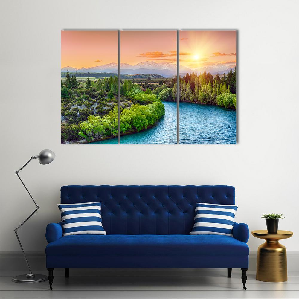 Sunset Over Winding River Bend Canvas Wall Art in orange, green and blue, 3 panel horizontal set hung on a wall