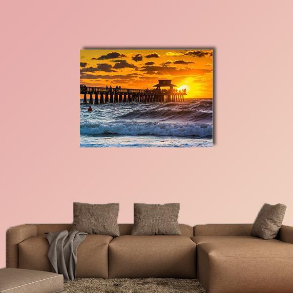 Sunset Over Fishing Pier Canvas Wall Art in orange, yellow and blue, single panel hung on a wall