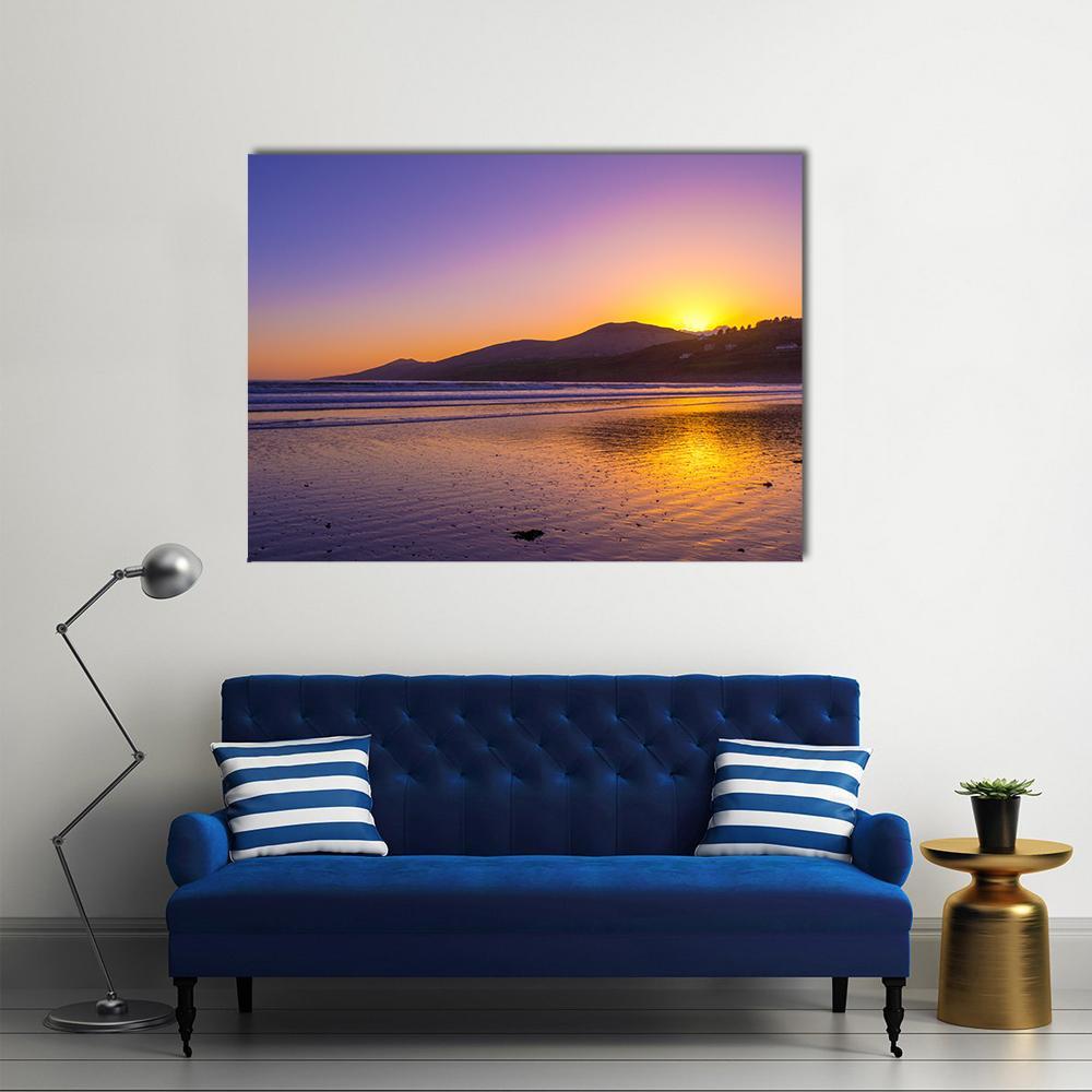 Sunset Over Beach and Distant Hills Canvas Wall Art in orange, yellow and purple, single panel hung on a wall