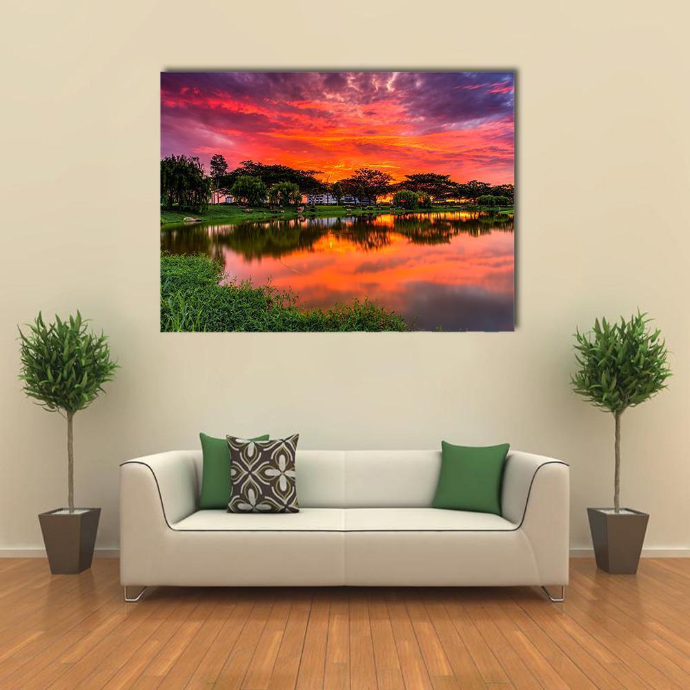 Sunset Over Lake with Tree Reflection Canvas Wall Art in orange, green and purple, single panel hung on a wall