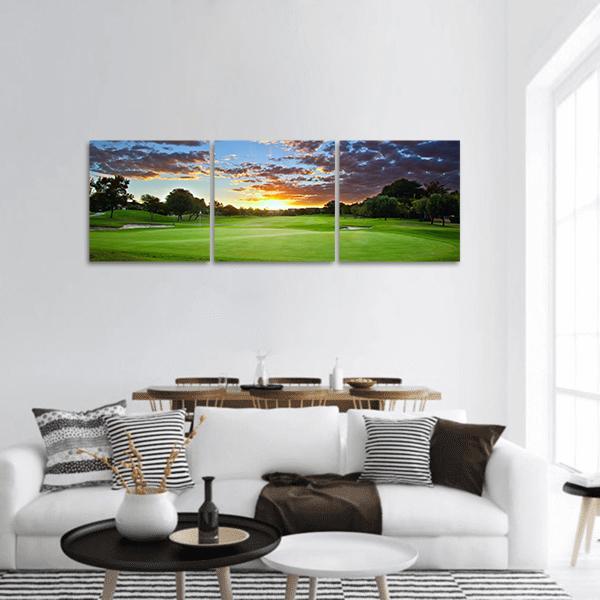 Sunset Over the Golf Course Panoramic Canvas Wall Art in orange, green and blue, hung on a wall