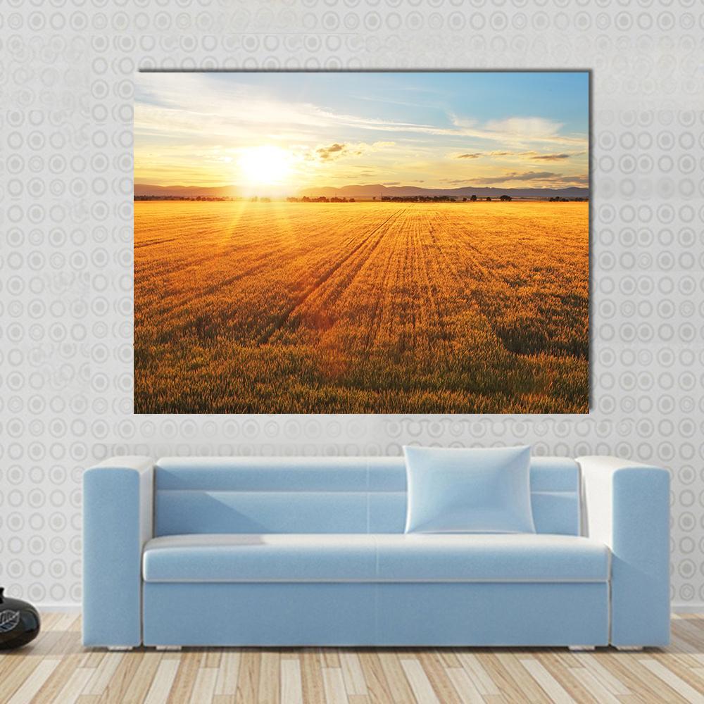 Sunset Over Wheat Field Canvas Wall Art in orange, yellow and blue, single panel hung on a wall