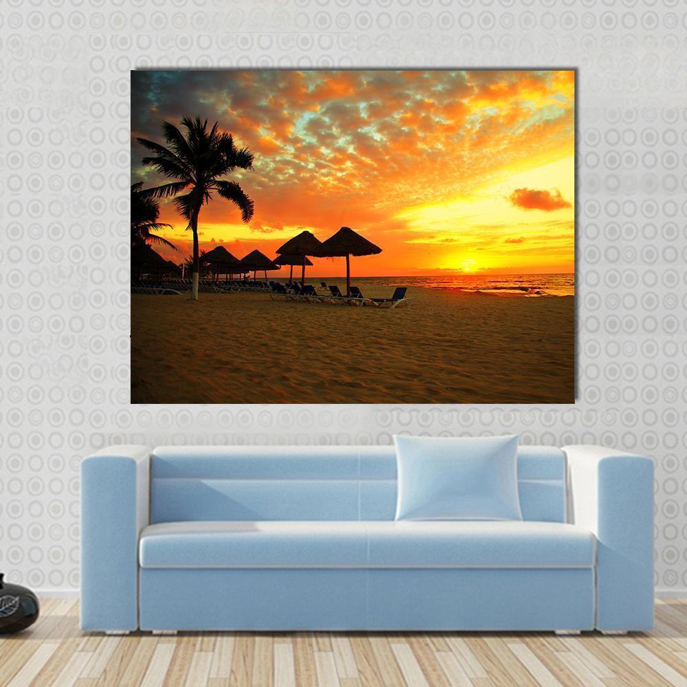 Sunset Scene at Tropical Beach Resort Silhouette Canvas Wall Art in black, orange and yellow, single panel hung on a wall