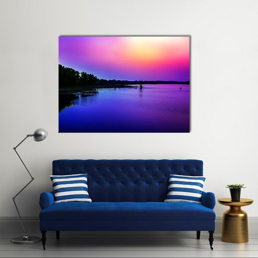 Sunset Sky Over Riverbank Canvas Wall Art in blue, purple and pink, single panel hung on a wall