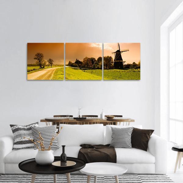 Dutch Windmill at Sunset Panoramic Canvas Wall Art in orange, yellow and green, hung on a wall