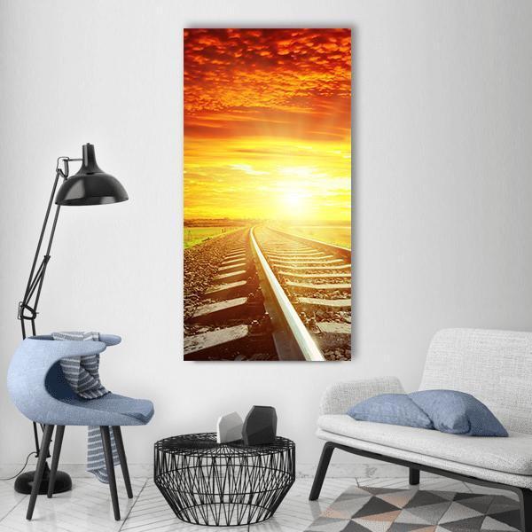 Sunset Over Railway Tracks Vertical Canvas Wall Art in brown, orange and yellow, single vertical panel hung on a wall