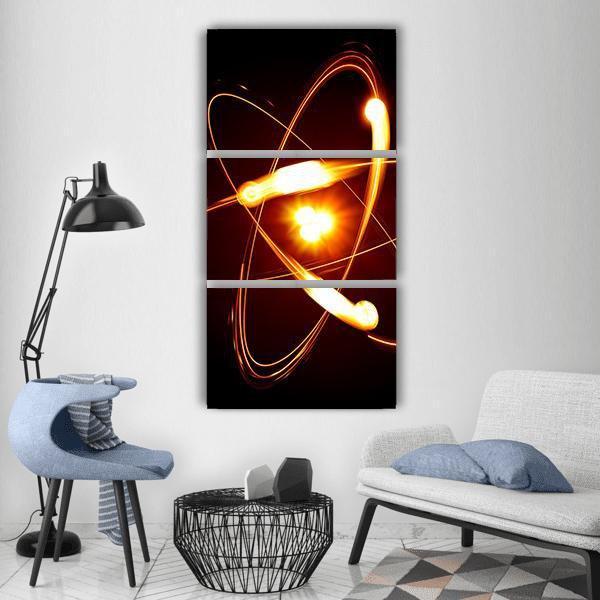 Atomic Model with Glowing Nucleus Vertical Canvas Wall Art in black, orange and yellow, single vertical panel hung on a wall