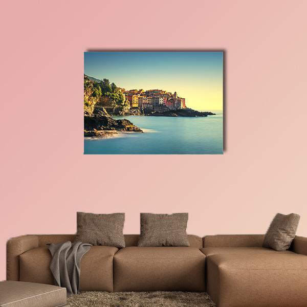 Colorful Clifftop Coastal Village Canvas Wall Art in brown, yellow and blue, single panel hung on a wall