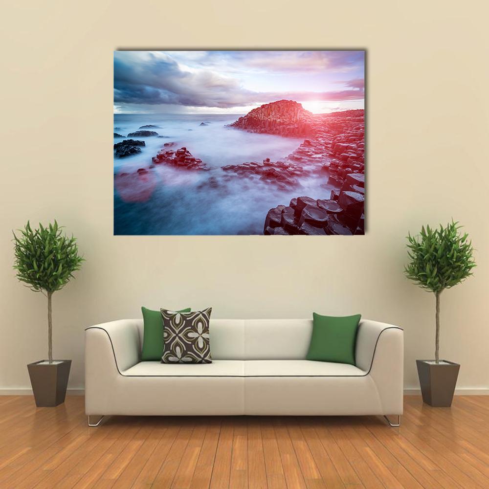 Basalt Coast at Sunset Canvas Wall Art in orange, blue and pink, single panel hung on a wall