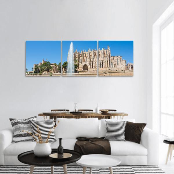 Palma Cathedral with Fountain and Palm Trees Panoramic Canvas Wall Art in beige, brown and blue, hung on a wall
