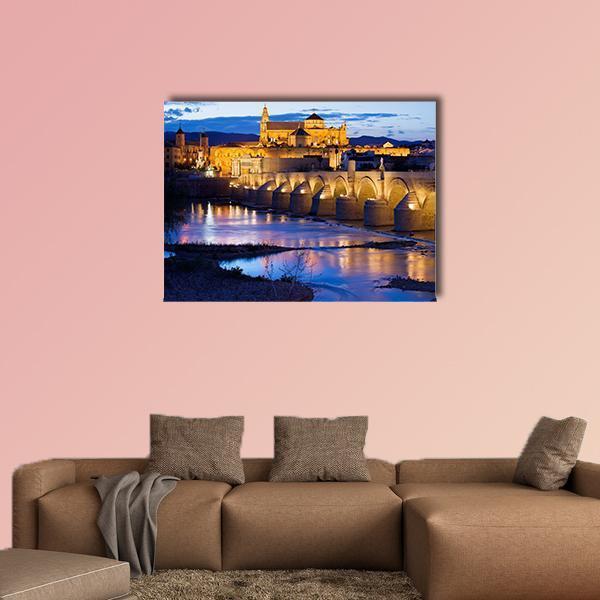 Roman Bridge and Great Mosque, Cordoba at Dusk Canvas Wall Art in orange, yellow and blue, single panel hung on a wall