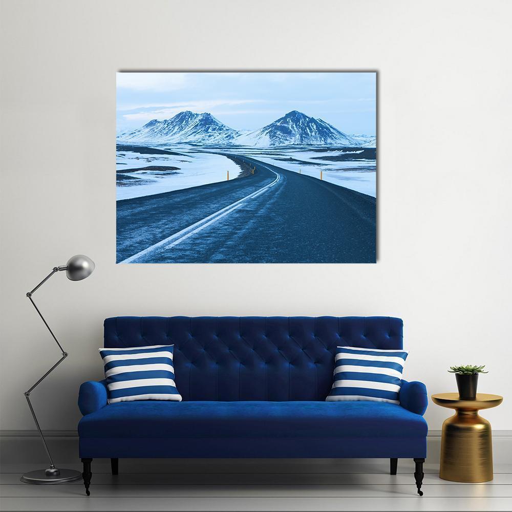 Winter Road Through Snow-capped Mountains Canvas Wall Art in white, gray and blue, single panel hung on a wall