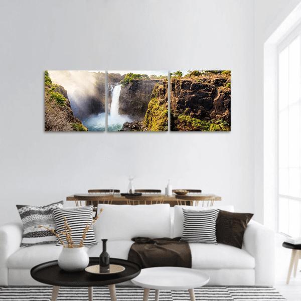 Victoria Falls Mist Over Rocky Cliffs Panoramic Canvas Wall Art in white, brown and green, hung on a wall
