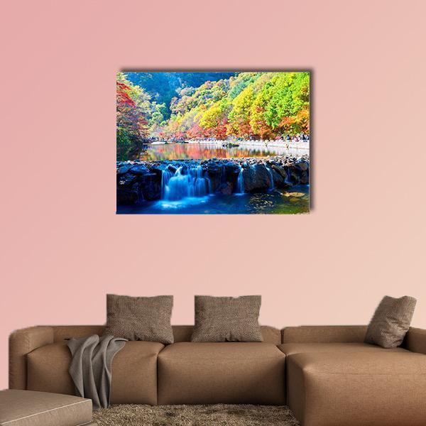 Waterfall in Autumn Valley Canvas Wall Art in orange, green and blue, single panel hung on a wall