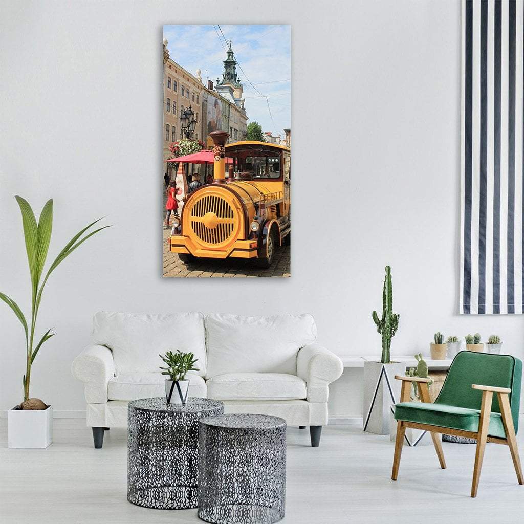 Yellow Tourist Train in Lviv Market Square Vertical Canvas Wall Art in beige, yellow and blue, single vertical panel hung on a wall