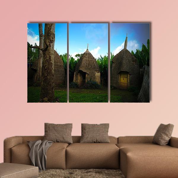 Dorze Tribe Village with Thatched Huts Canvas Wall Art in brown, green and blue, hung on a wall