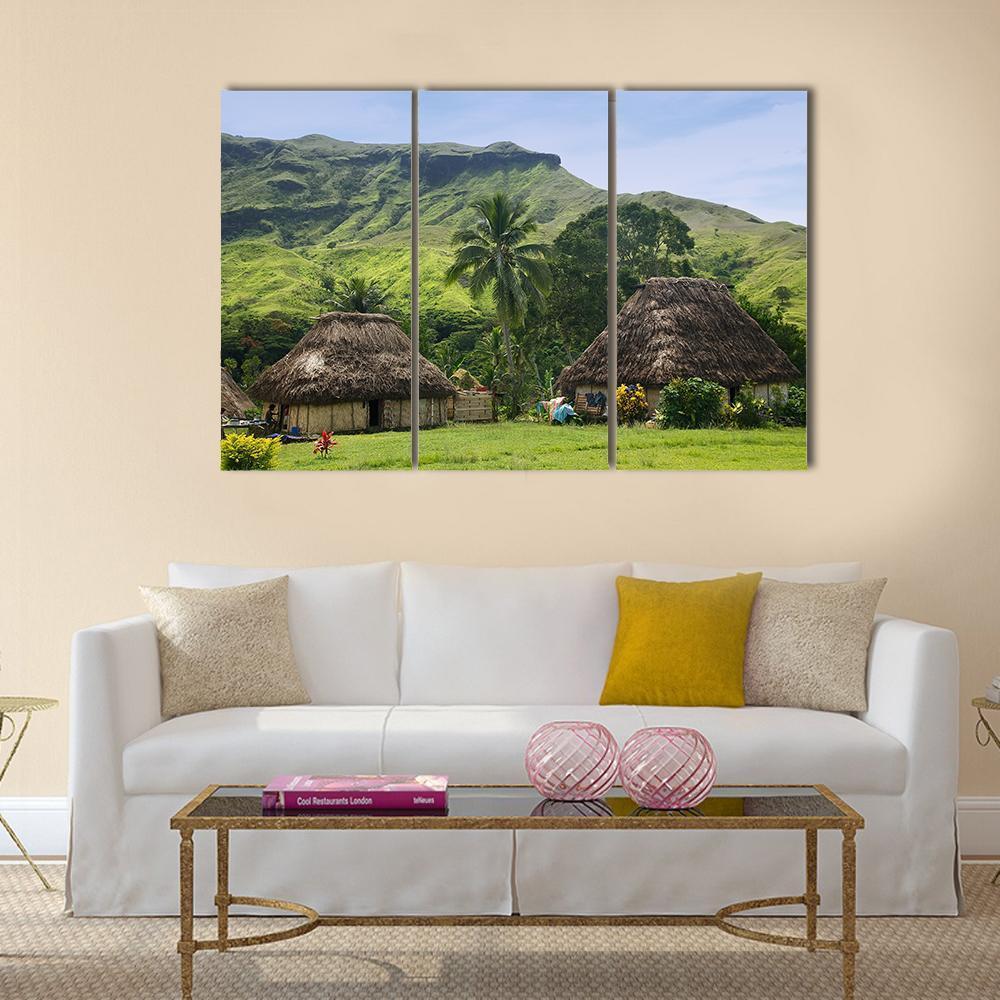 Traditional Huts in Navala Village Canvas Wall Art in brown, green and blue, 3 panel horizontal set hung on a wall