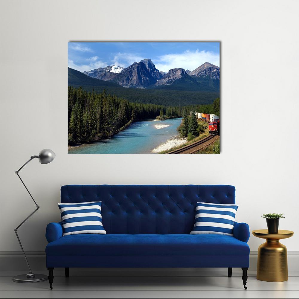Red Locomotive Along Turquoise River and Mountains Canvas Wall Art in red, green and blue, single panel hung on a wall