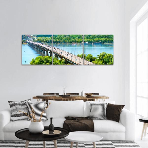 Long Bridge Over River with Trees Panoramic Canvas Wall Art in green and blue, hung on a wall