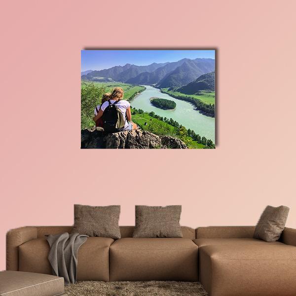 Travelers on Cliff Above Mountain River Valley Canvas Wall Art in brown, green and blue, single panel hung on a wall