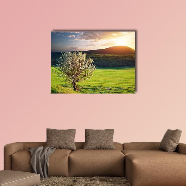 Tree in Mountain Meadow Canvas Wall Art in yellow, green and blue, single panel hung on a wall